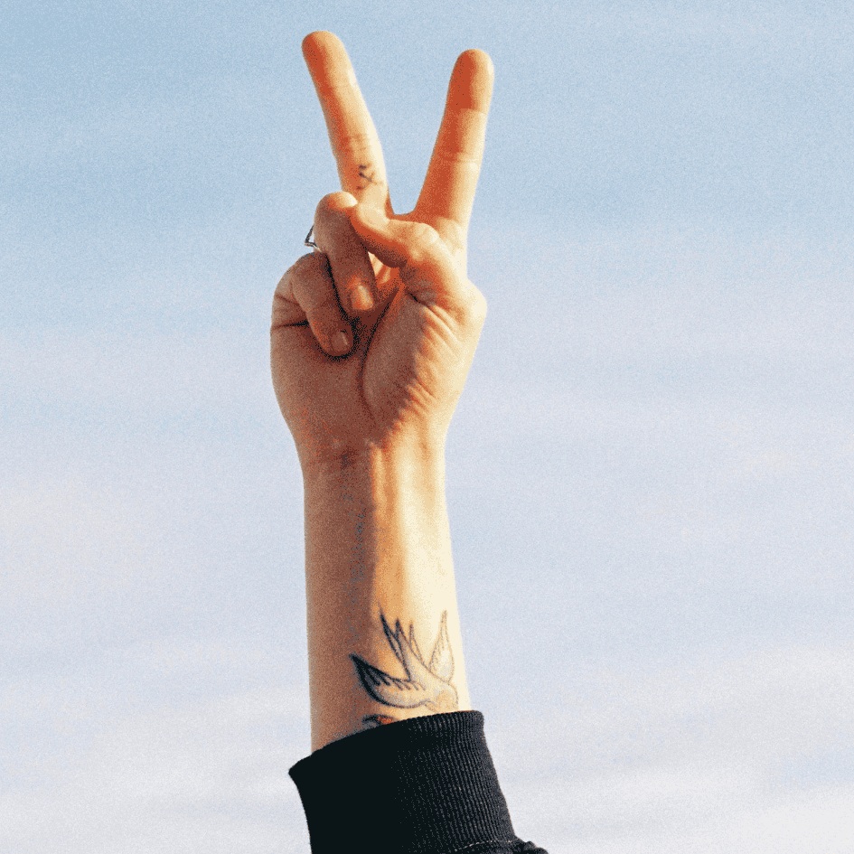 detalle de una mano con los dedos levantados haciendo el signo de victoria